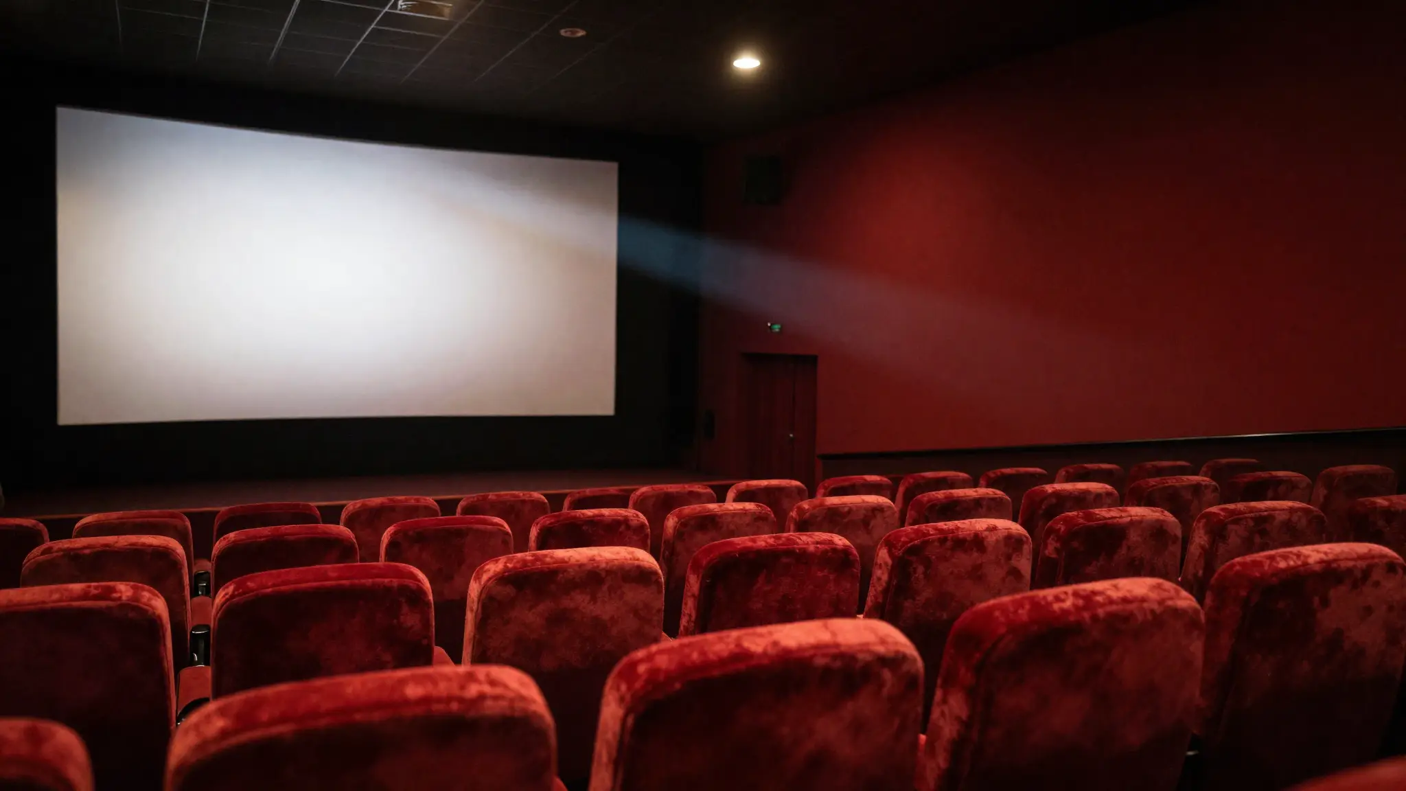 صالة سينما بمقاعد حمراء وشاشة عرض مضيئة تجسّد عالم الأفلام والسينما